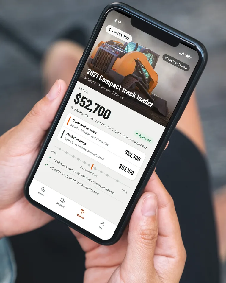 The field app in two hands: a 2021 compact track loader valued at $52,700 by two AI agents, one from comparable sales and one from market listings, 1.5 percent apart, so it was approved
