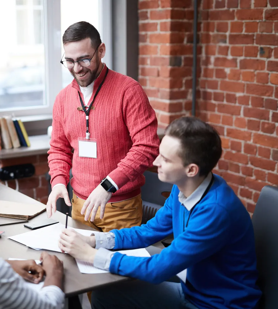 A team member showing two colleagues how to use new software at their desks